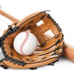 Home 8 A wooden baseball bat sits on a white surface next to a black and tan baseball glove with a baseball inside.