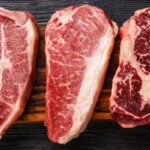 Home 2 Different cuts of steak lined up on a wooden board. Filet mignon is on the far right, and skirt steak is on the far left.
