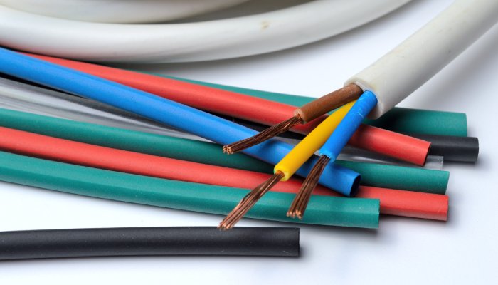 A three-core cable with a gray cable jacket wrapped up on a white surface and sitting on a pile of heat shrink tubing.