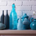 A close-up of a white, brick fireplace with beautiful blue decorations made of ceramics, glass, and plastic.