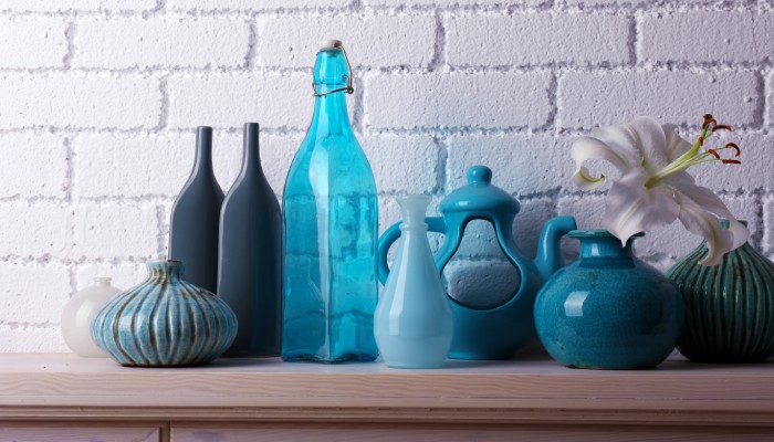 A close-up of a white, brick fireplace with beautiful blue decorations made of ceramics, glass, and plastic.