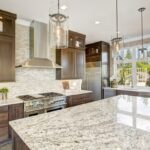 A luxurious residential kitchen with wooden cabinets and a stone countertop on an island in the center of the room.
